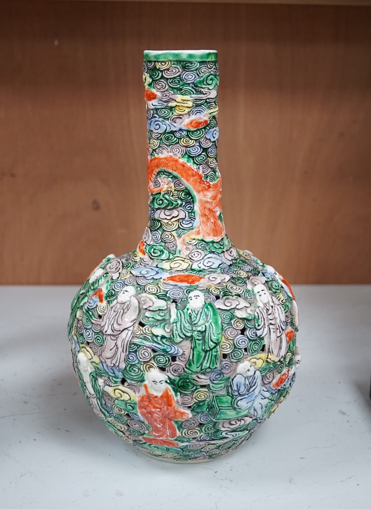 A Chinese moulded and reticulated porcelain eighteen luohan bottle vase, early 20th century, 34cm high. Condition - good